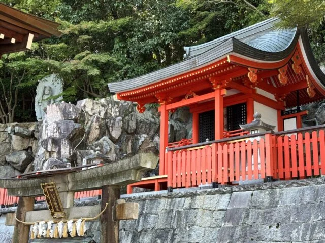 朱色の小社と石仏を横から見た写真
