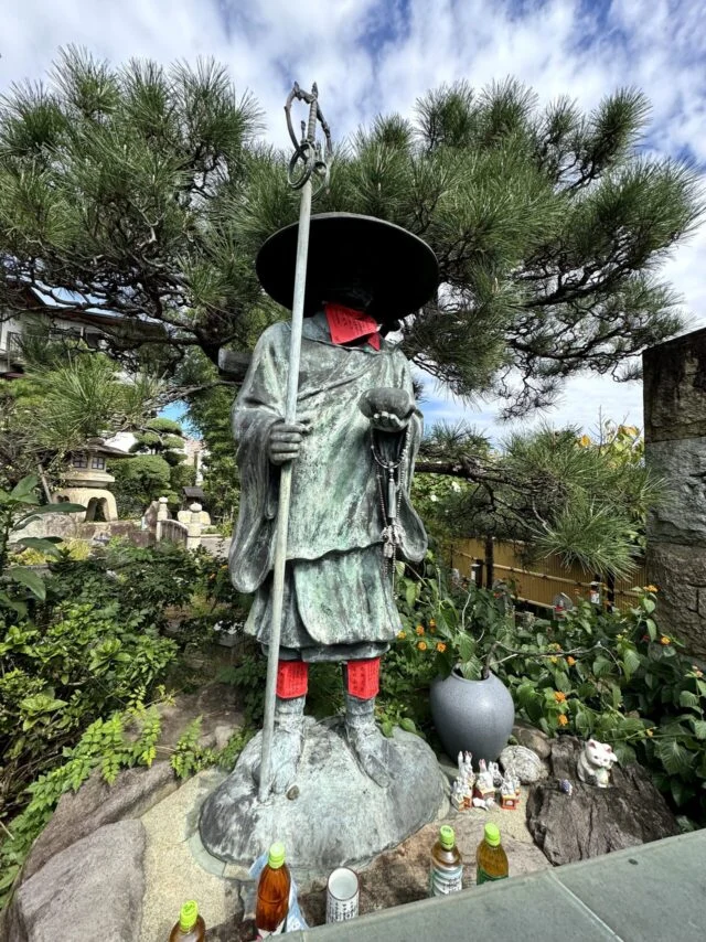 境内に立つ傘を持つ石仏