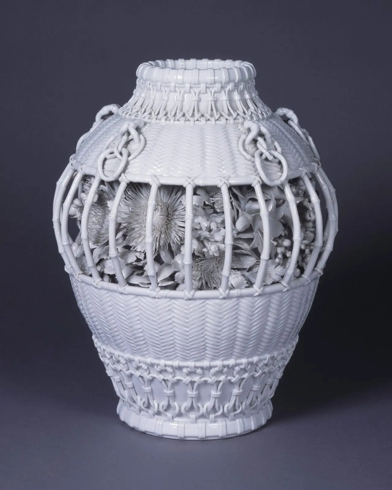 兵庫陶芸美術館公式掲載の出石《白磁貼花菊文籠形壺》。白磁で籠と花を細密に表した作品。