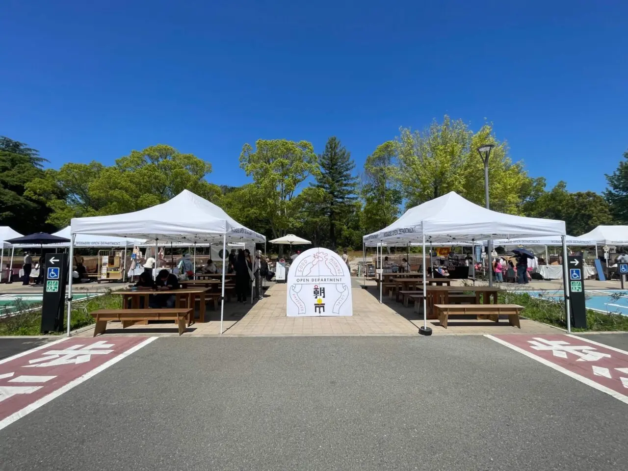 ムサシオープンデパート朝市の会場風景。日岡山公園第一駐車場前に並ぶテントとベンチ。