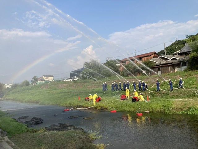 神戸市公式イベントサイト掲載の押部谷明石川まつり会場イメージ。消防団が川辺で一斉放水する様子。