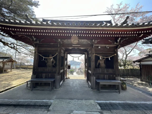 大避神社の神門と左右の仁王像、門の向こうに見える坂越の町