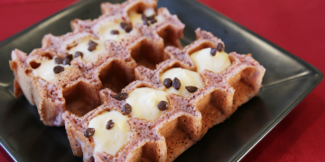 甲南大学コラボとして公式サイトに掲載された、黒い皿に並ぶワッフル型の焼き菓子の写真
