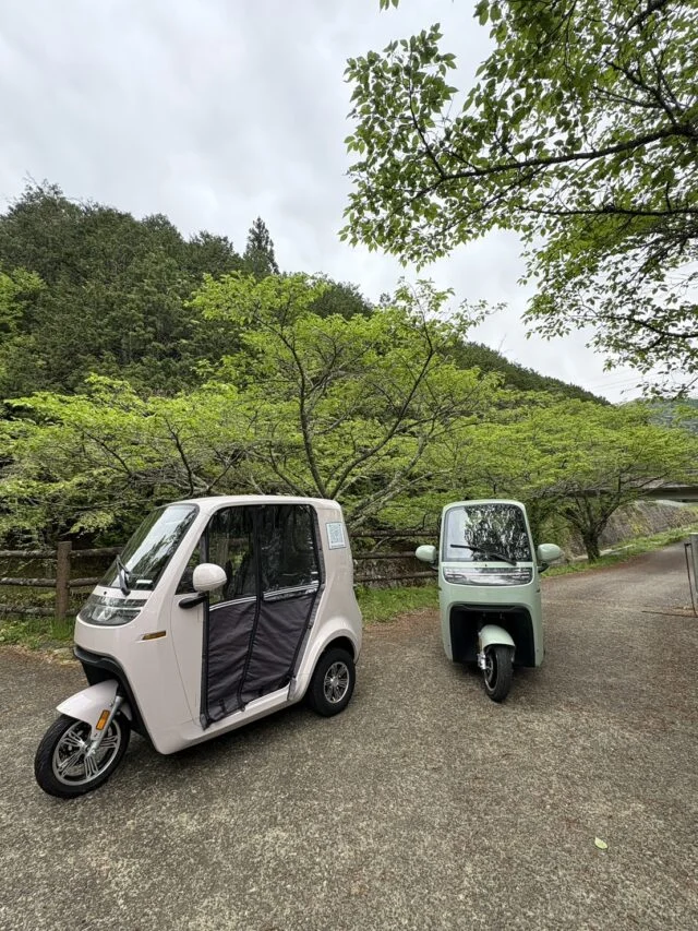 丹波市観光協会が公開した電動トゥクトゥクの写真。屋外に白色と淡い緑色の車両が1台ずつ写っている。