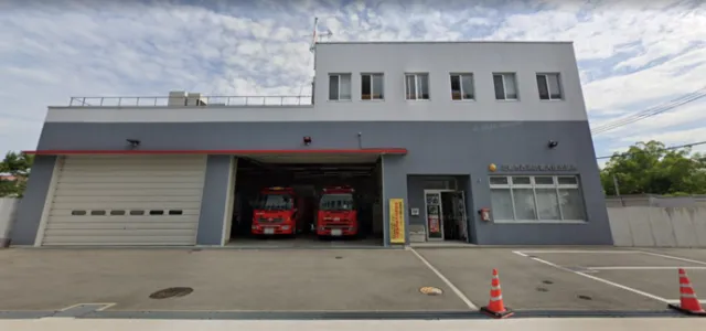 西消防署大庄出張所の灰色の庁舎。開いた車庫に赤い消防車が見える