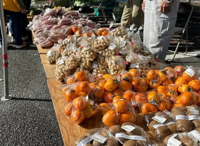 前年の西谷収穫祭で袋入りの野菜や柿が並ぶ販売台