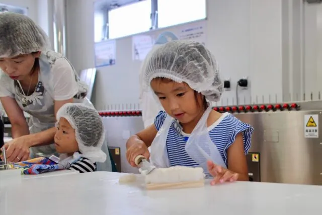 白い帽子とエプロンの子どもが、かまぼこ作りを体験している様子（写真はイメージ）