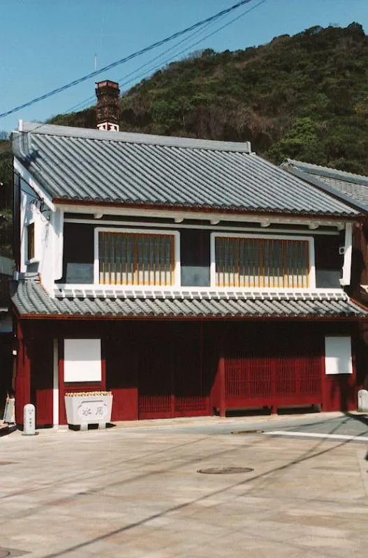 かどめふれあい館の外観。白い窓枠と朱色の格子の町家。