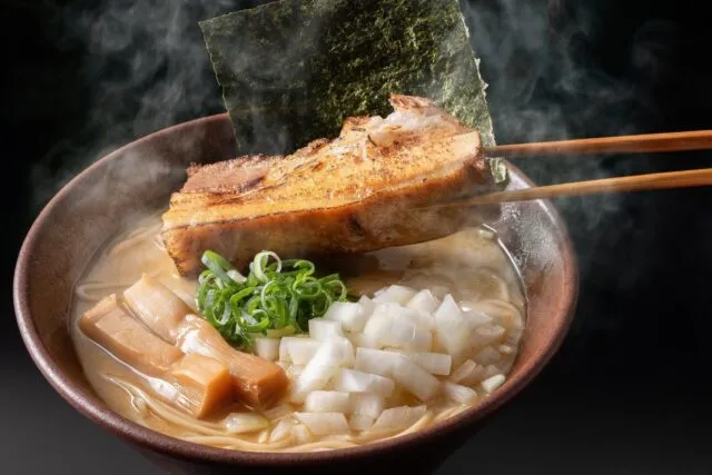 木八ラーメンの煮豚とんこつラーメン 厚切り炙りチャーシュー。厚切りのチャーシューに玉ねぎと太メンマがのる