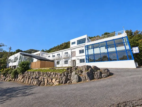 白い外壁に青い窓枠のhotel ISLET setouchiの外観