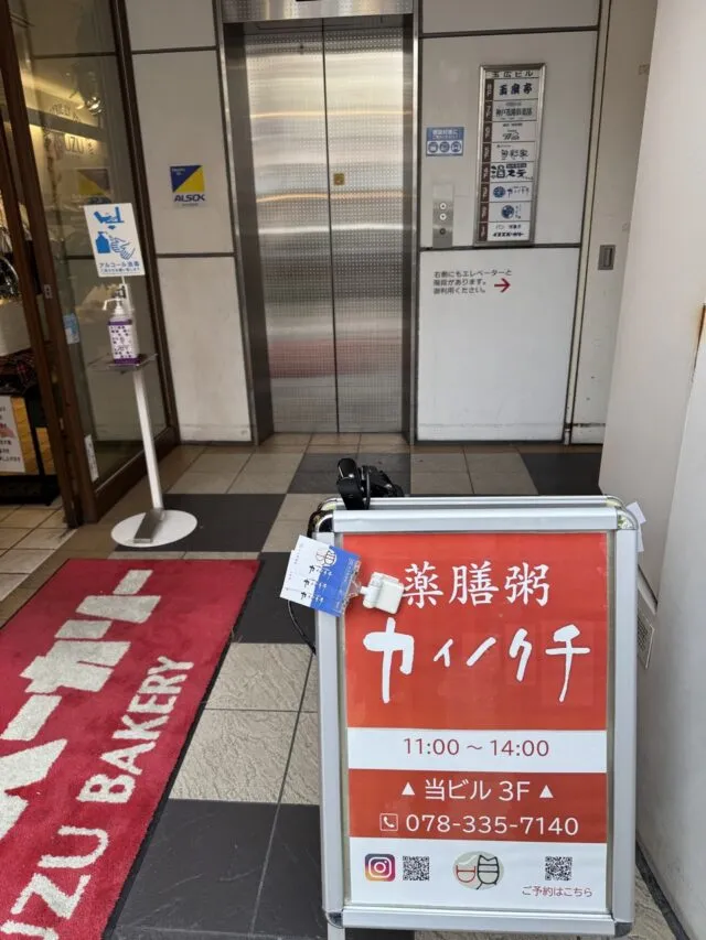 エレベーター前にカイノクチ・薬膳粥・3F・電話番号の赤い看板。（2025年1月7日撮影）