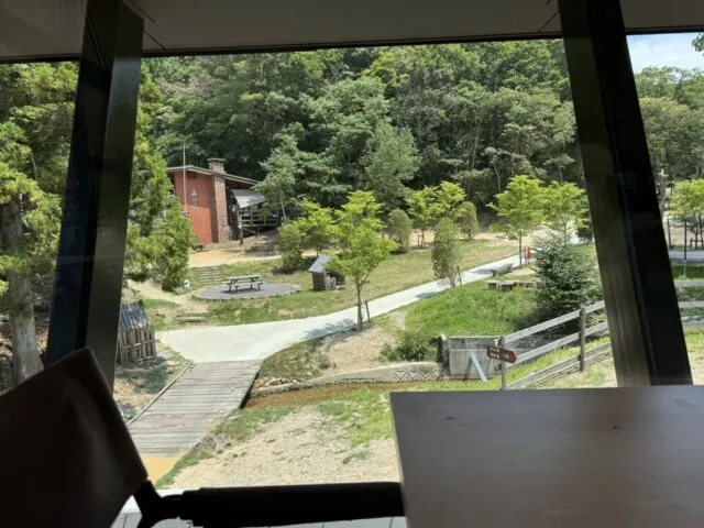 大きな窓の向こうに見える緑と木の通路