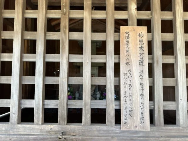 妙見大菩薩の名札と格子越しの石の塔の細部
