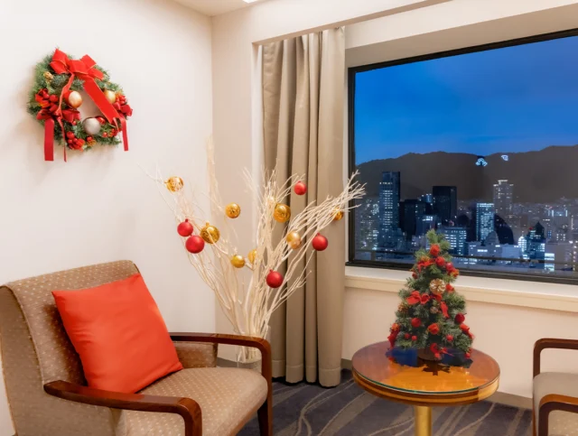 ホテルオークラ神戸のクリスマスコンセプトルーム。窓から神戸の夜景、室内にミニツリーとリース（ホテル公式画像）