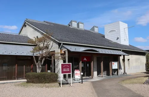 瓦屋根、白壁、木の入口がある伊藤清永記念館の外観。