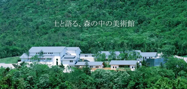 山林の緑を背に、白い壁と灰色屋根の建物が分かれて配置された兵庫陶芸美術館の公式紹介写真。