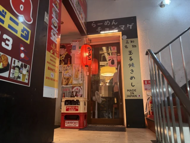 店名看板と赤い提灯がある神戸三宮店の入口。ガラス越しの第三者の顔は処理済み