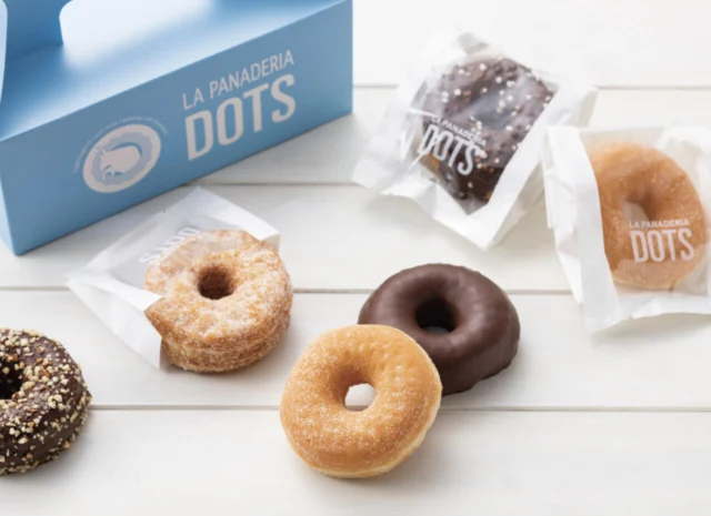DOTSのリング型ドーナツ。砂糖をまぶしたもの、チョコレートで覆ったものと青い箱