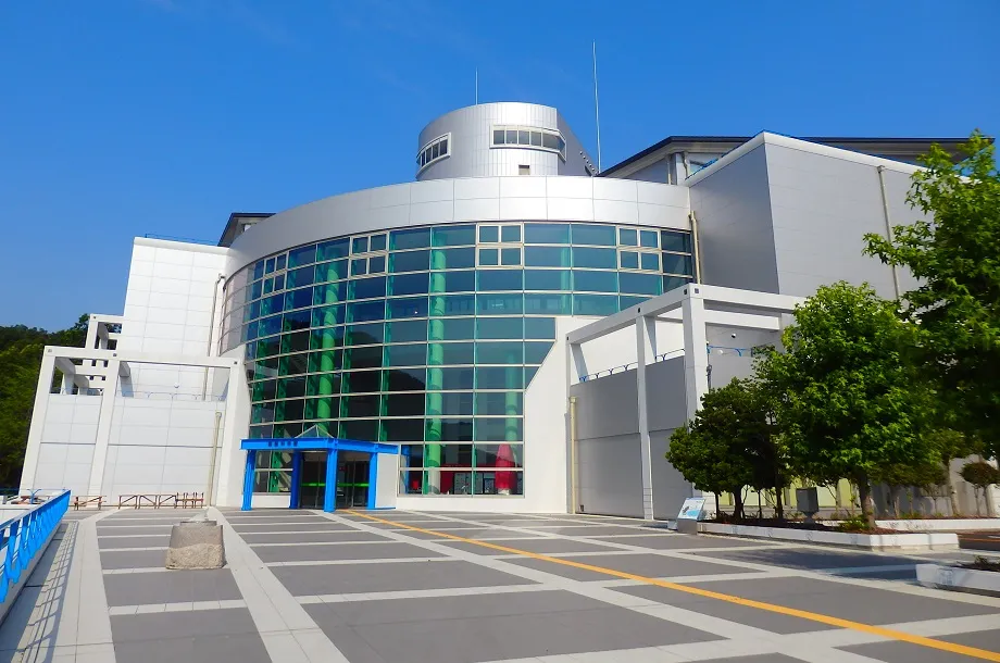 姫路科学館の銀色の外壁と曲面ガラス、中央の青い入口と上部の円筒形展望室