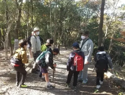 太子町の公式案内に掲載された文化財めぐりの様子。木立の中で参加者が説明を聞いている