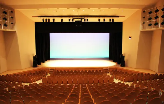 市川町文化センターひまわりホールの客席と舞台。赤系の座席が並び、正面にスクリーンがある