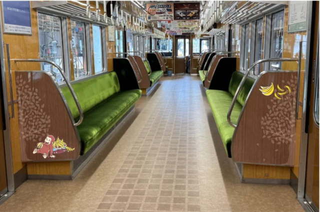 のせでん号の公式車内写真。緑のロングシート、木目の壁、座席端のジョージの装飾