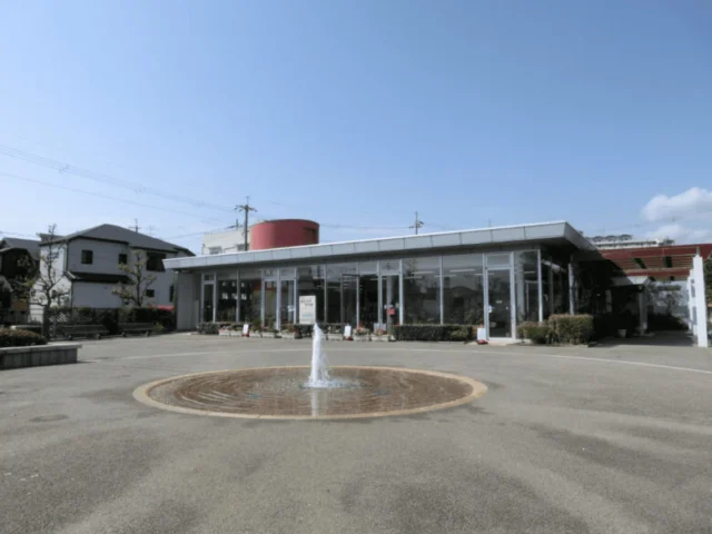 みどりのプラザの施設外観。平らな屋根、ガラス張りの入口、前庭の円形噴水