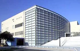 スワンホールの外観。淡い色の横長の建物に湾曲した大きなガラス面がある