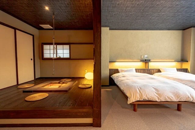 運営発表の客室写真。左に木床と座卓、右に2台のベッドがある和の空間