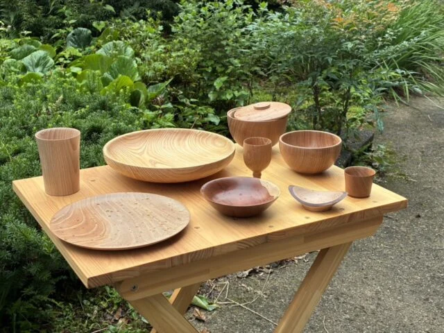 木目の異なる皿、椀、ふた付きの器やカップが台に並ぶ、中村寿木工作品展の公式紹介写真