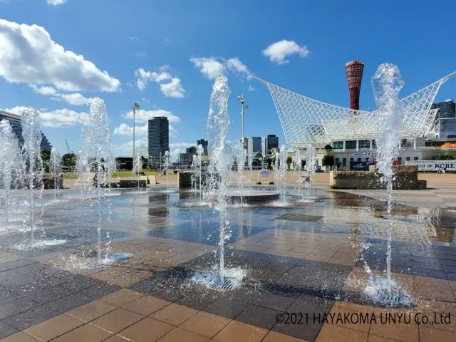 メリケンパークの噴水広場、赤い神戸ポートタワーと白い大屋根