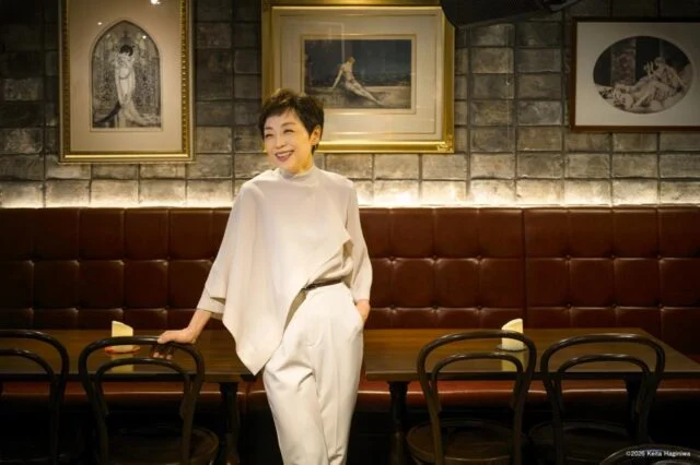 白い衣装で椅子に手を添えて立つクミコの公式公演紹介写真