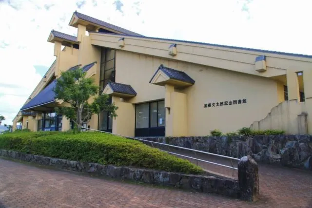 加藤文太郎記念図書館の黄土色の外壁、瓦の切妻屋根とスロープのある入口