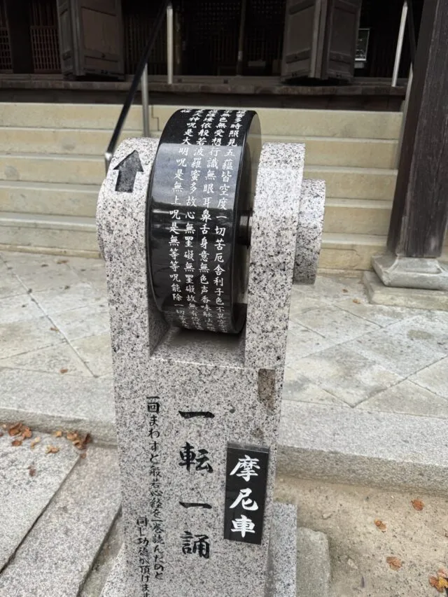 講堂前の摩尼車と「一転一誦」の石柱。