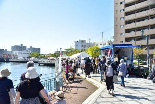 運河沿いの柵とレンガ舗装の遊歩道に、テントや来場者が並ぶ兵庫運河祭の会場風景