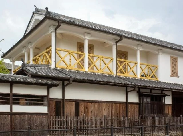 旧九鬼家住宅資料館の外観。瓦屋根、白い壁、黄色い手すりが見える