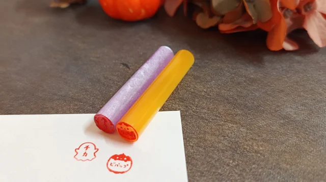 紫と黄色のはんこと、紙に押された赤いおばけ・かぼちゃの印面。ハロウィーンのはんこ作りの例