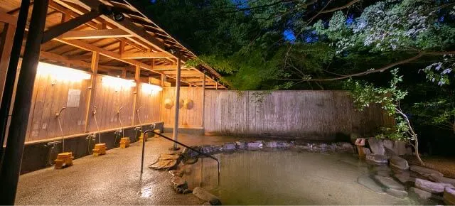 湯元うえやまの野天風呂。木の屋根の下に洗い場があり、岩囲いの湯船がある
