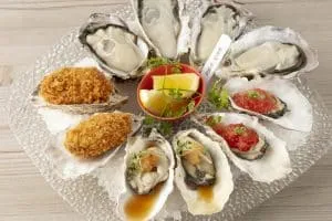 The Oyster Bar Kobeの公式メニュー掲載写真。生牡蠣・焼き牡蠣・フライの盛り合わせ