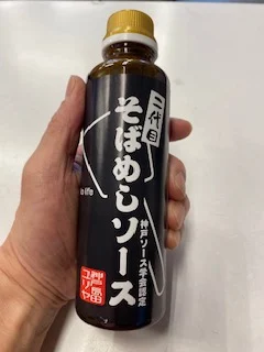 金色のふたと黒地に白文字のラベルが付いた、二代目そばめしソースの瓶