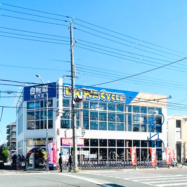青い看板とガラス面が目印のダイワサイクル西宮鳴尾店の2階建て外観