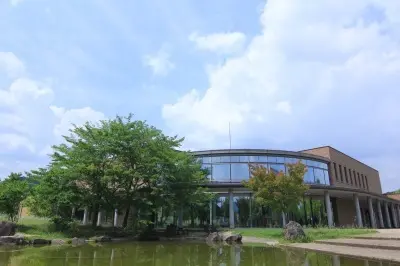 ガラス面と茶色の外壁、前庭の池がある猪名川町生涯学習センター