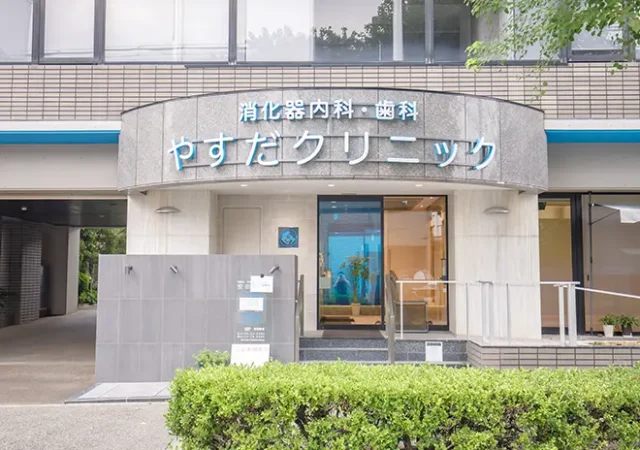 やすだクリニックの外観。入口には消化器内科・歯科の青い看板がある