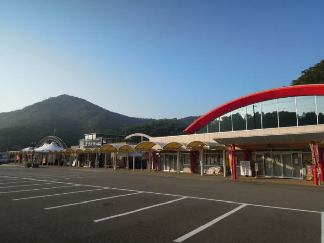 赤いアーチ屋根の農産物販売センターと、低い屋根が連なる道の駅いながわの外観