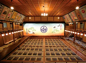 出石永楽館の館内。木の桟敷席、舞台の緞帳、左右の手書き看板