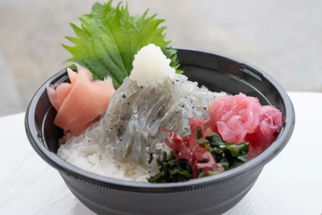 えびす丸の生しらす丼。透明なしらす、刺身、海藻などを盛り付けた黒い丼
