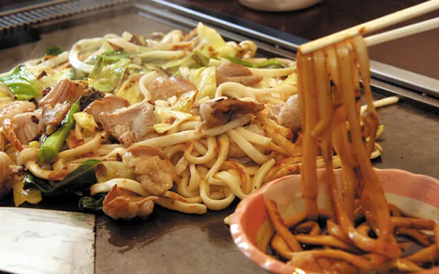 大会公式サイトが紹介する佐用名物のホルモン焼きうどん。鉄板上のうどんと野菜、ホルモン、つけだれ