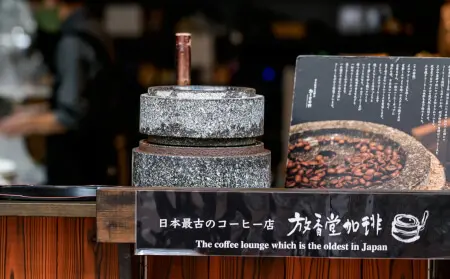店頭に置かれた灰色の円筒形の石臼。上部に木の持ち手がある