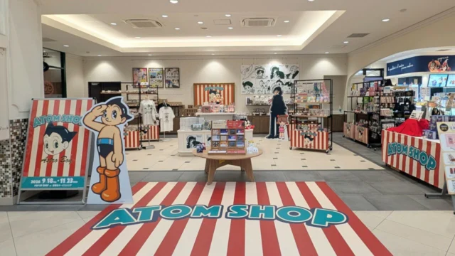 宝塚北SA店内中央のATOM SHOP。赤白の売り場、商品棚とアトム・ブラックジャックのパネル
