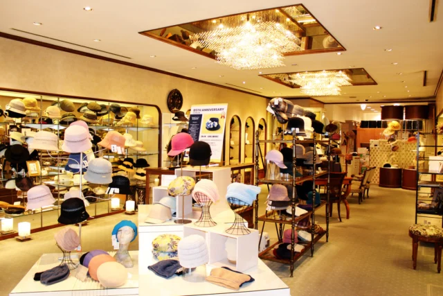 暖色の照明の下にハットやベレーを並べた神戸トアロード本店の店内